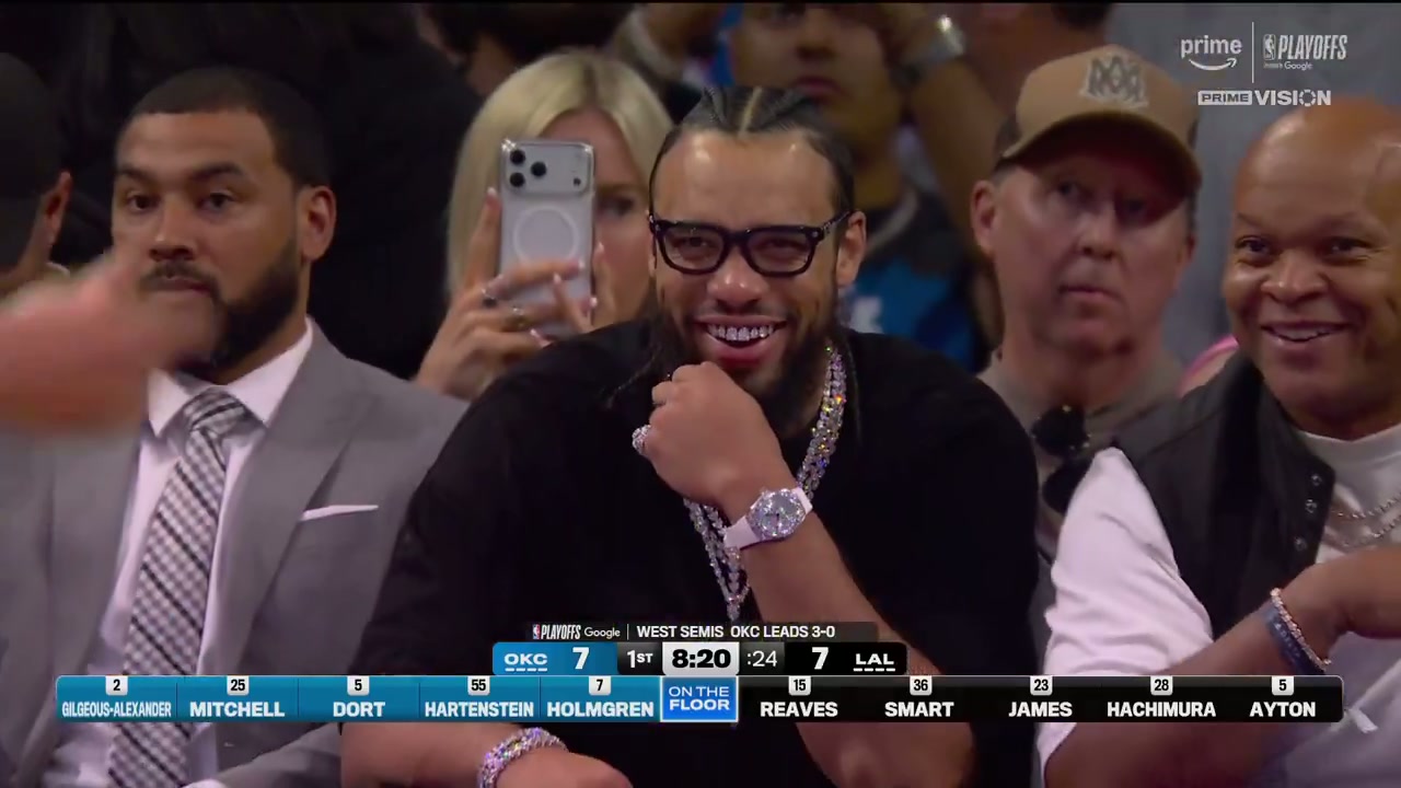 Dillon Brooks smiles courtside in a diamond grill with layered chains, watch and ring visible during Thunder versus Lakers Game 4