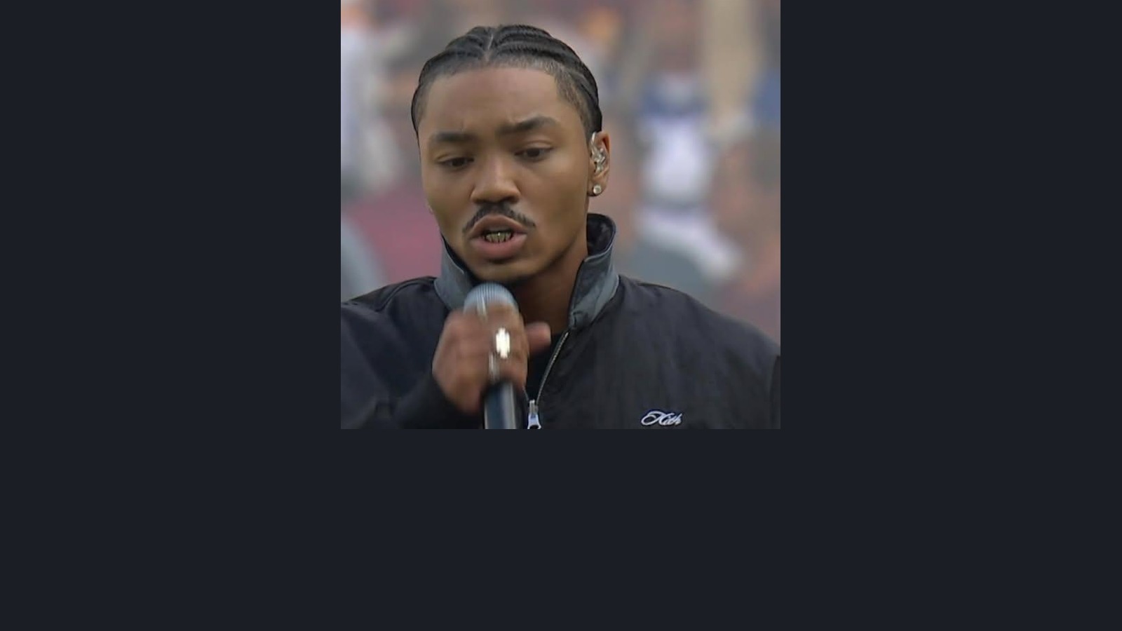 Josh Levi singing the national anthem in London with his face and white-gold Grillz visible